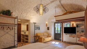 A bedroom with a bed, a sofa, a television, and a ceiling fan.