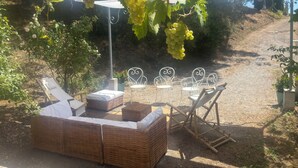 A garden area with wicker furniture, a pergola with grapevines, and a gravel path. - Charming bed and breakfast in Giono country. (Manosque)
