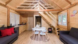 A wooden cabin interior with a dining table, two sofas, a staircase, and a fireplace. - Ranczo Targówka - Wooden Cabin 1 with Sauna (Miłaczewskie Młyny)