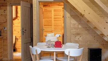 Een houten interieur met een eettafel en stoelen, een trap en een deur die naar een andere kamer leidt.