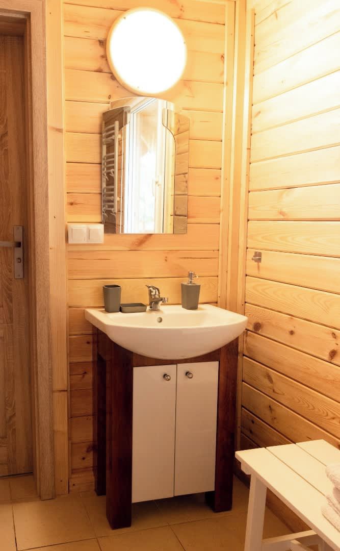 Un bany de fusta amb un mirall rodó, un lavabo i un armari.
