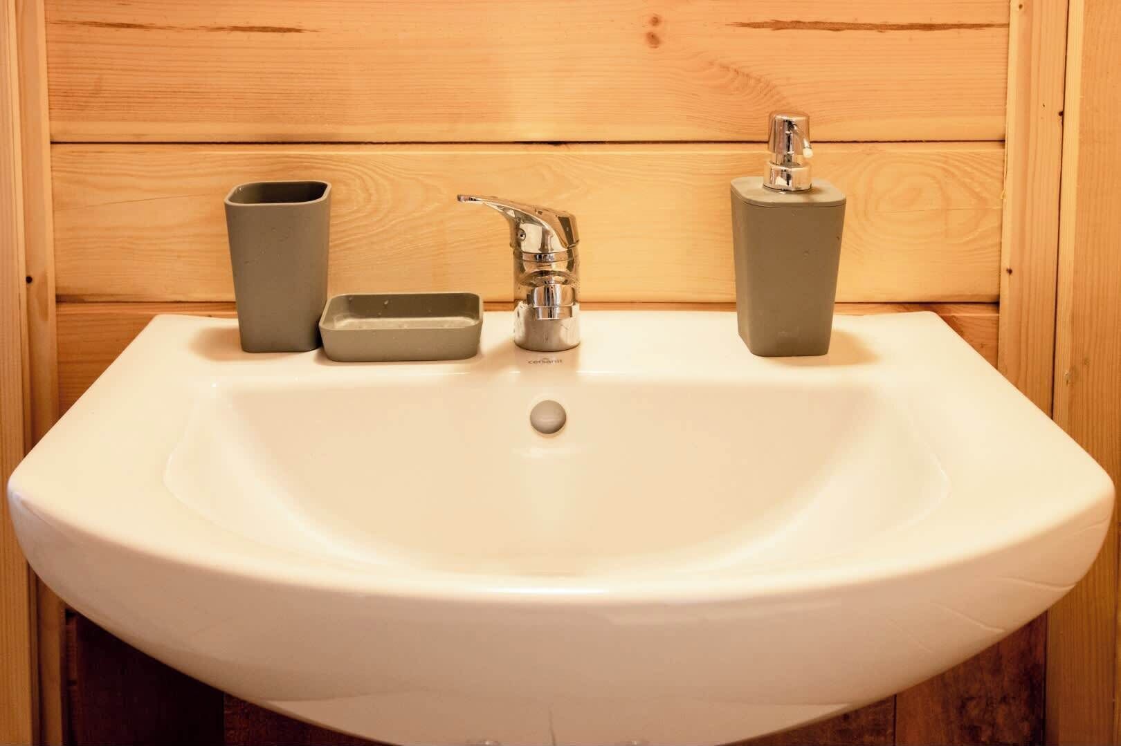 Ein weißes Waschbecken mit einem einzelnen Wasserhahn, einer Seifenschale und zwei Seifenspendern.