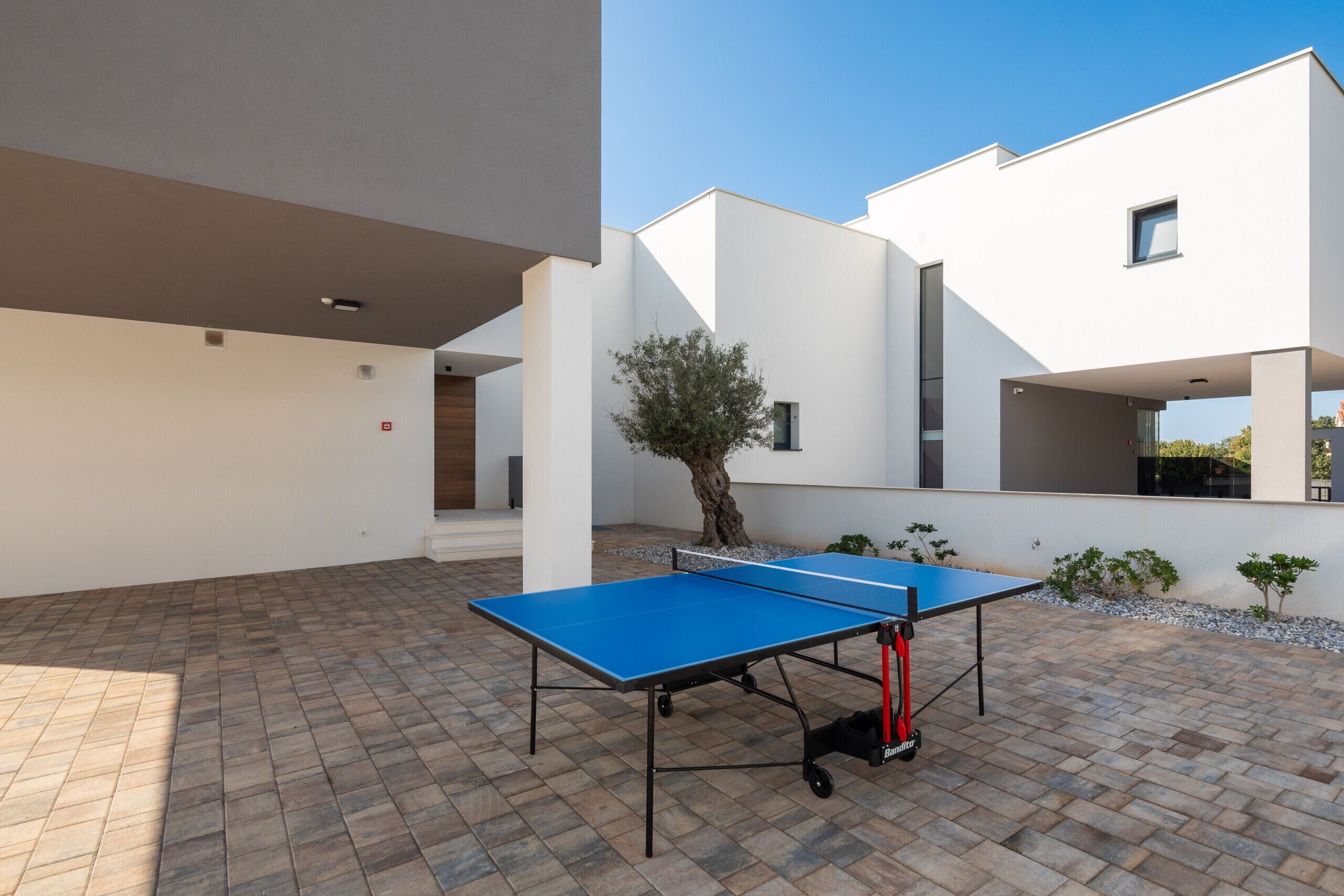 An outdoor ping pong table in a courtyard with a modern building in the background.