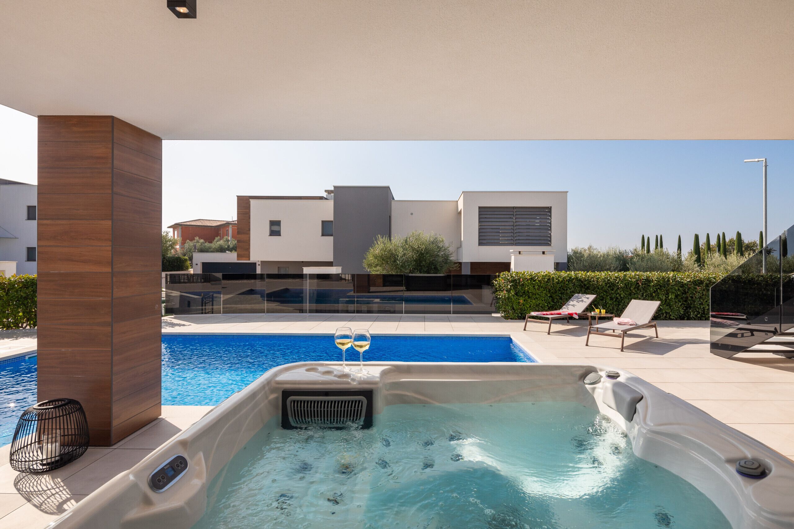 Een modern buitenzwembad met een jacuzzi, ligbedden en een helder uitzicht op de omliggende gebouwen.
