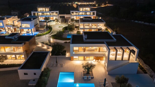 Een modern wooncomplex met meerdere onderling verbonden huizen, een centraal zwembad en buitenzitplekken.