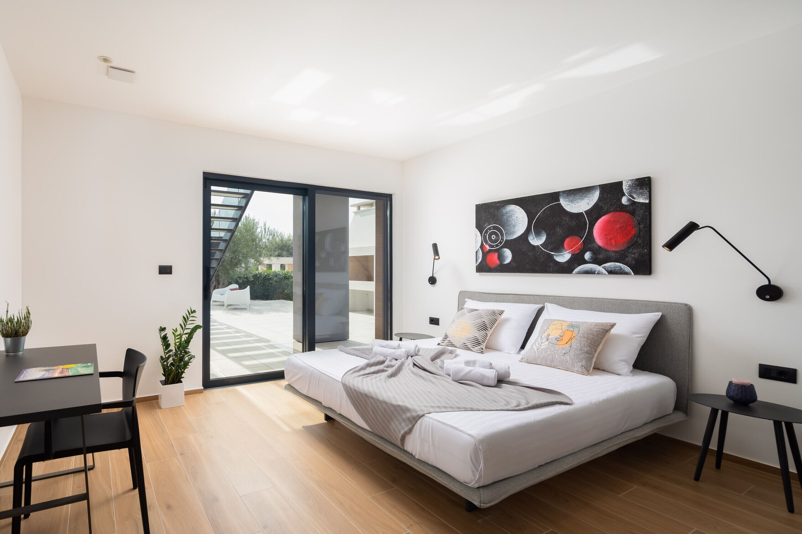 Une chambre moderne avec un lit, un bureau et une grande fenêtre.