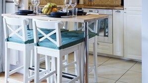 Une cuisine moderne avec des meubles blancs, une table à manger avec des chaises et un luminaire suspendu.