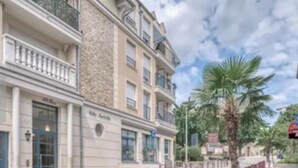 Un immeuble à plusieurs étages, doté d’une façade en pierre, de balcons et d’une enseigne indiquant « Hôtel ».