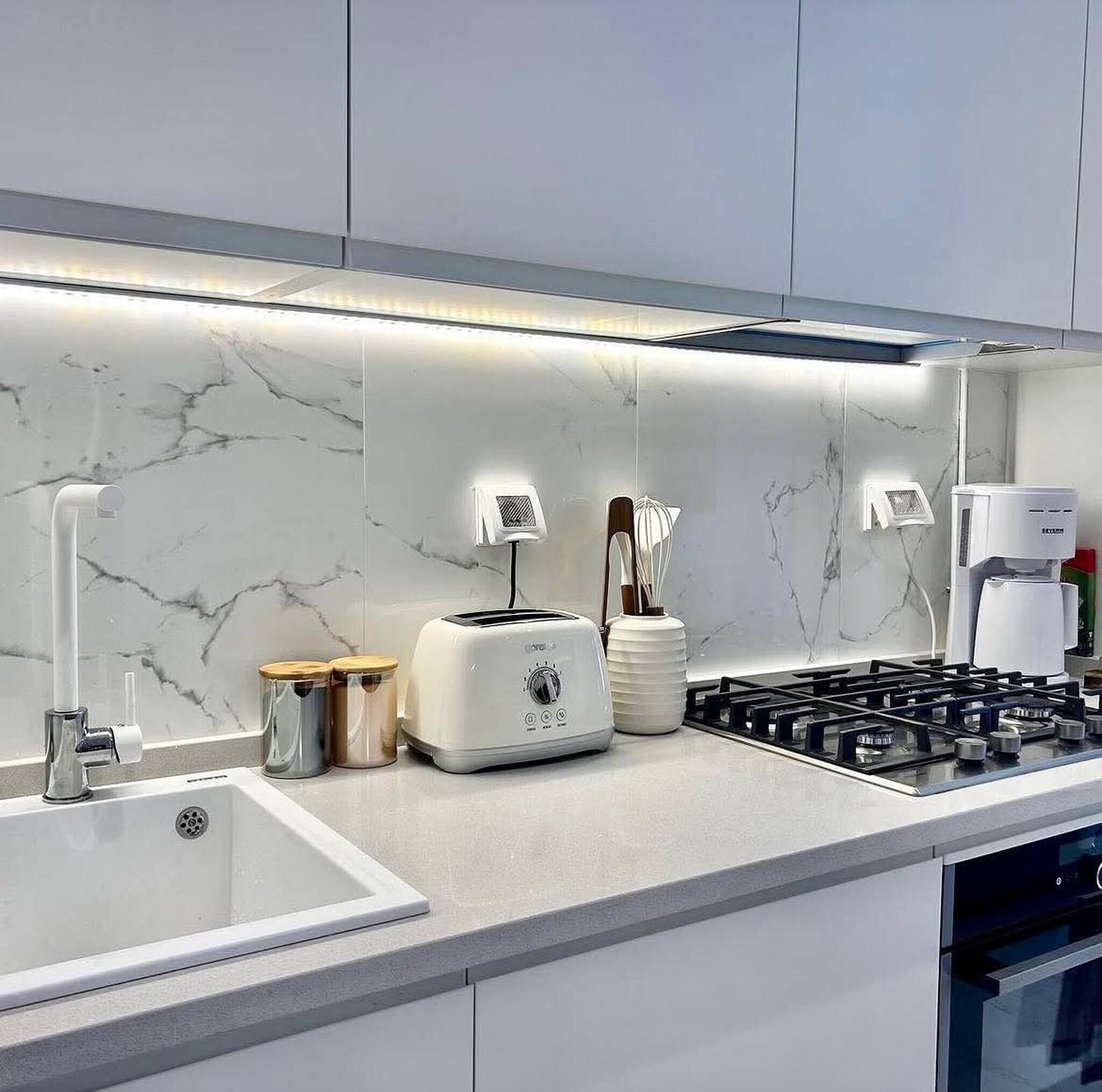 A modern kitchen with a built-in gas stove, a white toaster, and a coffee maker.