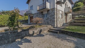 Un bâtiment à deux étages avec des murs en pierre, des balcons et une allée gravillonnée.