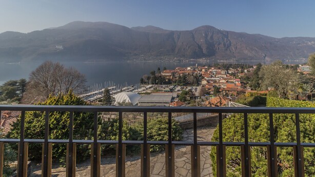 Une ville au bord d’un lac, avec des montagnes en toile de fond, un port de plaisance et une vue depuis un balcon.