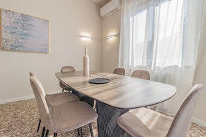 A conference room with a round table, beige chairs, a vase, and a painting on the wall.