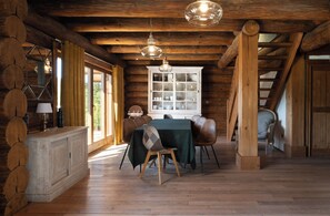 A rustic wooden interior with a dining table, chairs, and a cabinet. - Chalet Serenity - Sleeps 9 - Hot Tub (Liézey)
