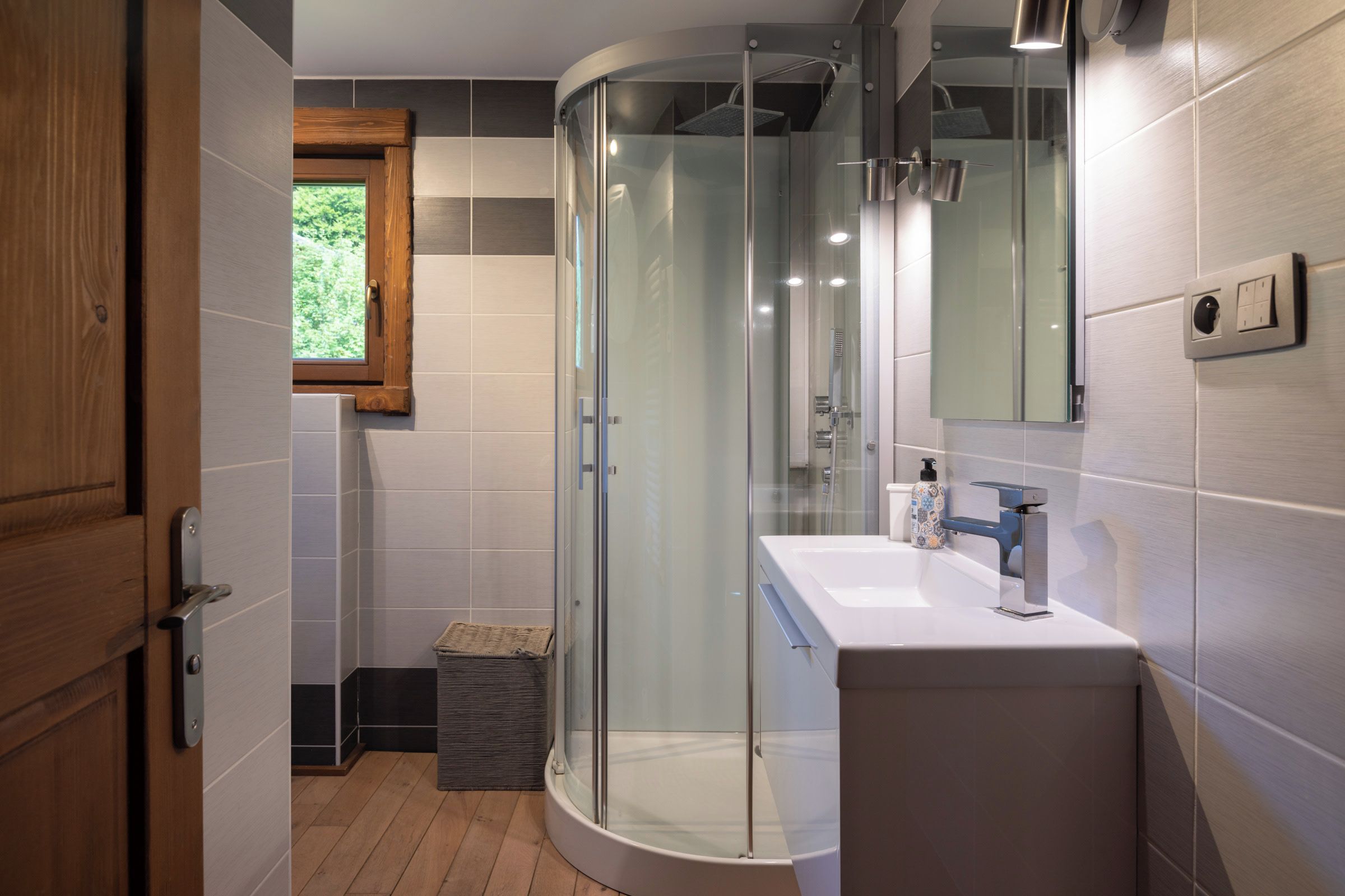 A modern bathroom with a glass-enclosed shower, a white sink, and a mirror.