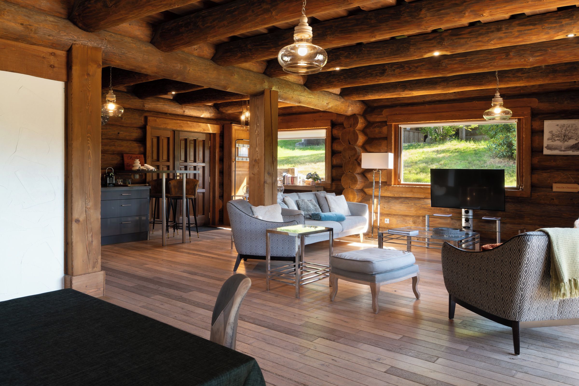 A log cabin interior with a living area, dining space, and a kitchen.