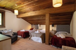 Un dormitorio acogedor en el ático, con vigas de madera, dos camas, un sofá y una pequeña mesa.