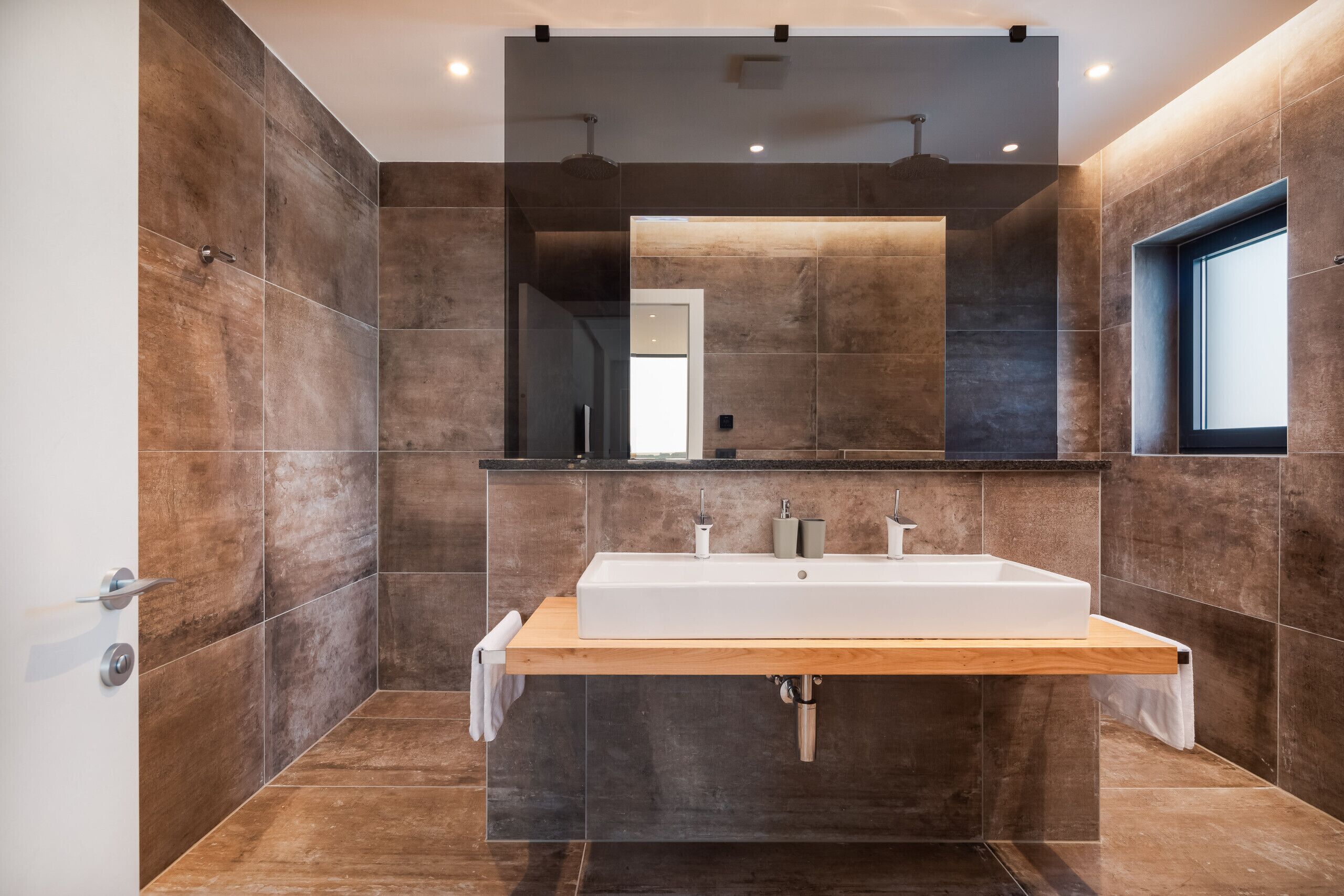 A modern bathroom with a large mirror, a wooden vanity, and a shower area.