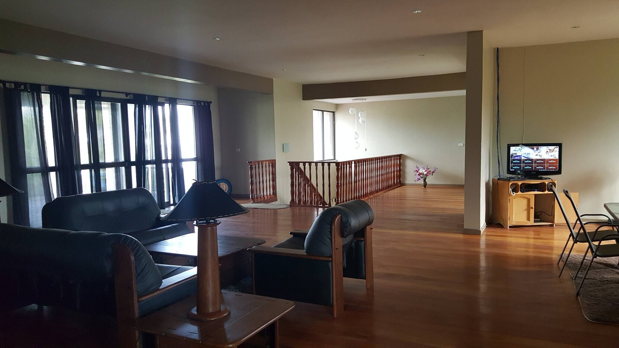 A spacious living room with a sofa, a coffee table, a TV, and a staircase leading to another level.