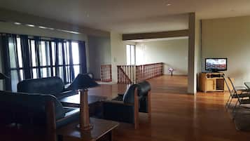 A spacious living room with a sofa, a coffee table, a TV, and a staircase leading to another level.
