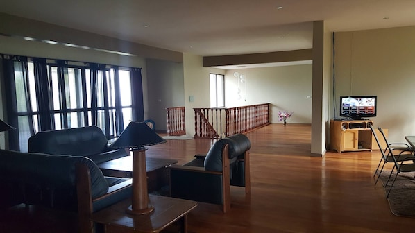 A spacious living room with a sofa, a coffee table, a TV, and a staircase leading to another level.