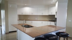 A modern kitchen with white cabinets, a granite countertop, a stainless steel sink, and a gas stove. - Seaview Drive, Executive Home (Sigatoka)