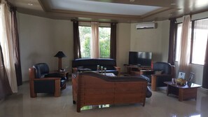 A living room with a sofa, two armchairs, a coffee table, a TV, and a small table with a lamp. - Seaview Drive, Executive Home (Sigatoka)