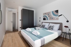 Ein modernes Schlafzimmer mit einem Bett, einem Nachttisch, einer Wandlampe und einer Tür zu einem anderen Raum.