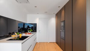 Et moderne køkken med en central ø, indbyggede apparater og udsigt gennem døren.