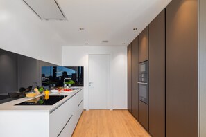 A modern kitchen with a central island, built-in appliances, and a view through the door. - Vivi Rent - Villa Old Olive VI (Vodnjan)