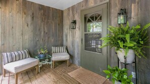 Eine gemütliche Veranda mit einer Bank, einem kleinen Tisch und Topfpflanzen.