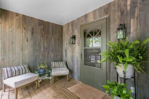 A cozy porch with a bench, a small table, and potted plants.