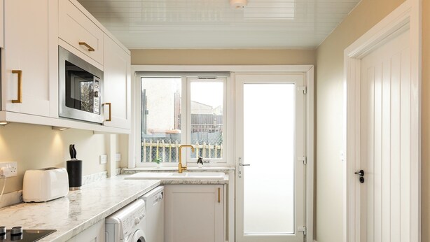 A compact kitchen with a washing machine, a microwave, and a toaster.