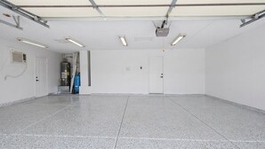 Een ruime, lege kamer met een gepoetste vloer, witte muren en een deur aan het einde.