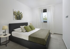 Ein modernes Schlafzimmer mit Bett, Nachttischen, einem Fenster mit Vorhängen und einem Wandbild.