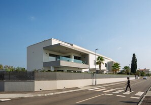 Ein modernes Gebäude mit flachem Dach, großen Fenstern und einem Balkon.