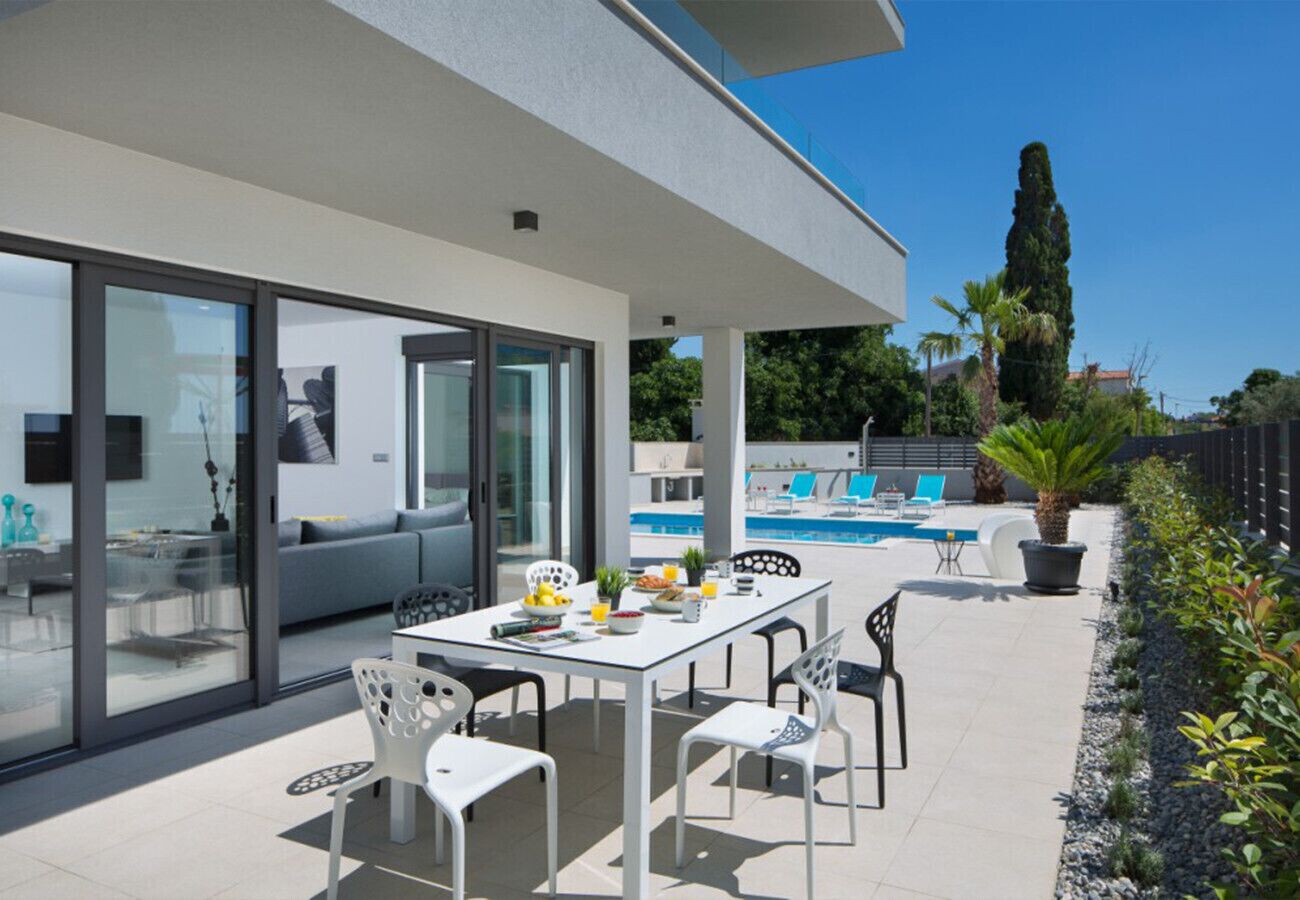 A modern house with a patio, a dining area, and a swimming pool.
