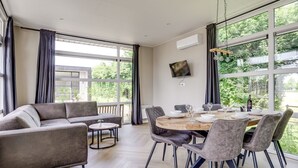 A modern dining area with a round table, grey upholstered chairs, and a grey sofa.