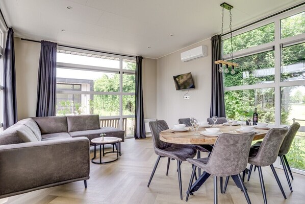 Un comedor moderno con una mesa redonda, sillas tapizadas en gris y un sofá de color gris.