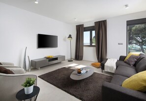 A modern living room with a flat-screen TV, grey sofa, and a coffee table. - Vivi Rent Fažana - Villa Fasana Penthouse 5 (Fažana)