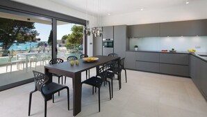 Une cuisine moderne avec un coin repas, de grandes fenêtres et une vue sur l’extérieur.