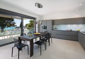 A modern kitchen with a dining area, large windows, and a view of the outdoors. - Vivi Rent Fažana - Villa Fasana Penthouse 5 (Fažana)