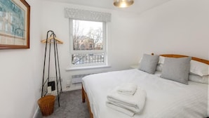 A bedroom with a bed, a window with a view, a hanging light fixture, and a framed picture on the wall. - Monkgate Cloisters - Free Parking (York)