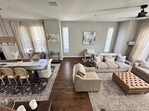 A spacious living room with a dining area, a sofa set, and a large ottoman. - Spacious 3-Story Heights Townhome • 3 King Beds (Houston)
