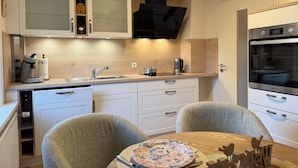 A modern kitchen with a built-in oven, a coffee maker, and a sink. - Cozy vacation apartment in Hahnenklee/Harz right on the edge of the forest with a large garden (Goslar)