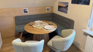 A cozy room with a round wooden table, two upholstered chairs, a bench, and a wall-mounted picture. - Cozy vacation apartment in Hahnenklee/Harz right on the edge of the forest with a large garden (Goslar)