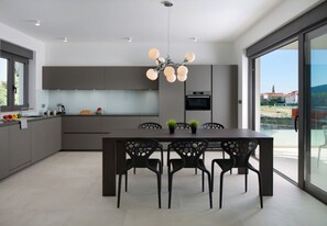 A modern kitchen with a dining area, a large window, and a view of the outside. - Vivi Rent Fažana - Villa Fasana Penthouse 5 (Fažana)