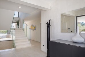 Ein modernes Interieur mit Treppe, einem großen Spiegel und einem schlichten Konsolentisch.