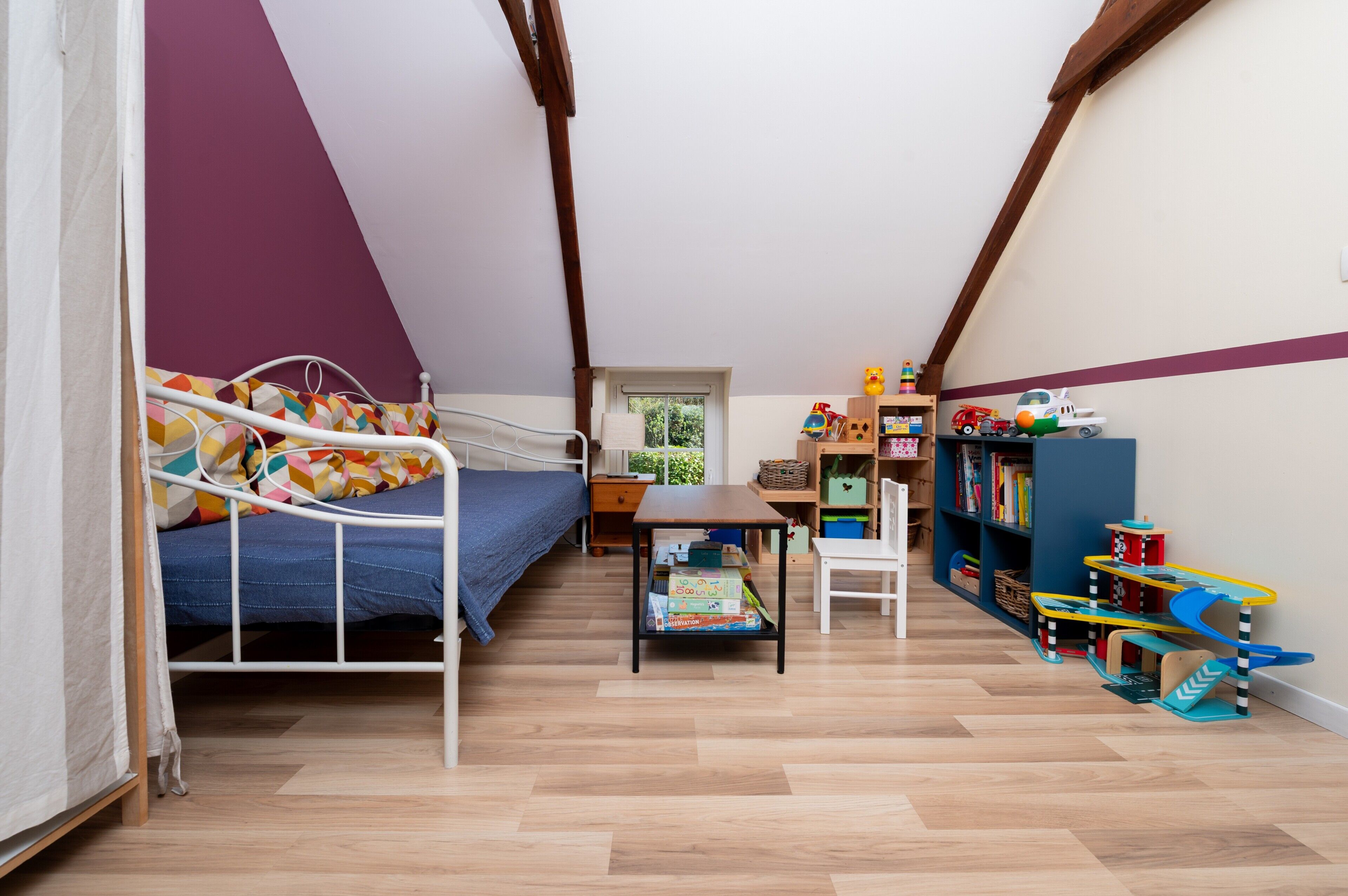 Une chambre avec un lit superposé, un bureau, une chaise et une bibliothèque remplie de jouets.