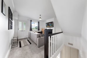 Un intérieur moderne avec un escalier, un canapé, un téléviseur et une fenêtre avec des rideaux.
