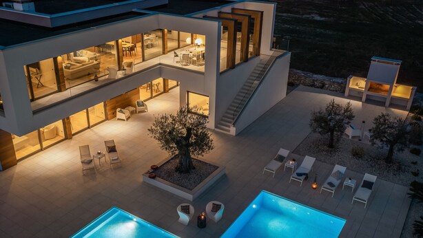Un edificio moderno a più piani con piscina, area salotto esterna e una scala.
